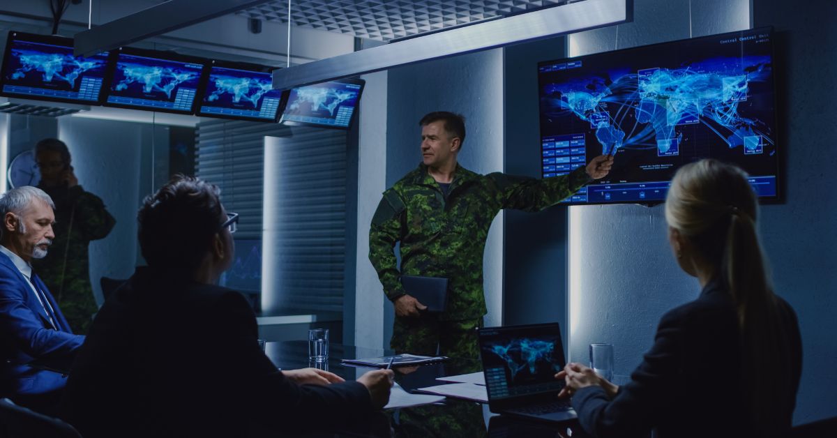 Military officials discussing strategies, a military official showing a satellite surveillance footage to the team